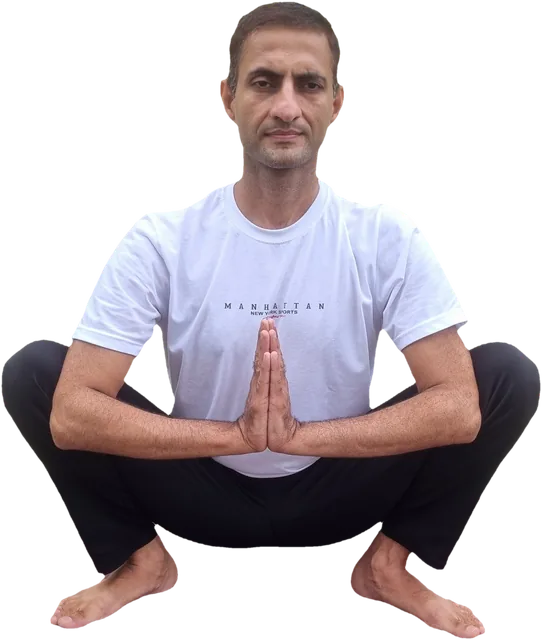 Sohan sitting in a low squat, palms joined at his chest, calm and facing the camera